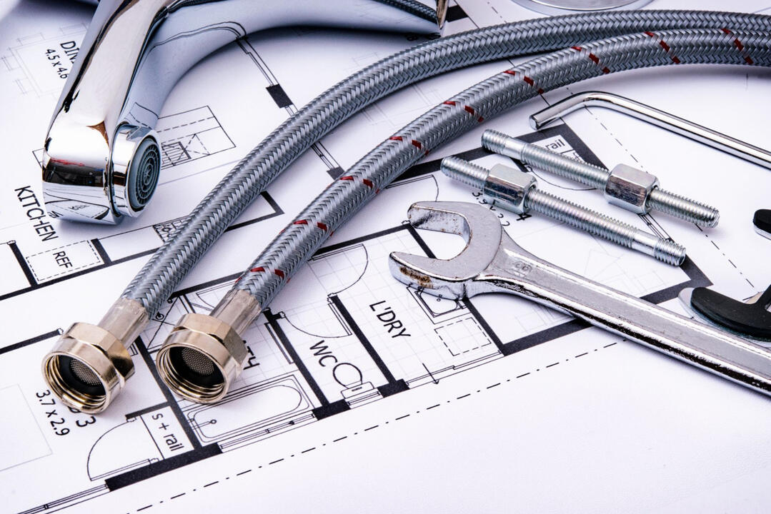 Complete Home Renovation Services Sydney | Design & Construction Solutions Plumbing fixtures, flexible water hoses, and renovation tools on architectural plans, representing full-service home renovation, bathroom remodeling, and construction projects in Sydney.